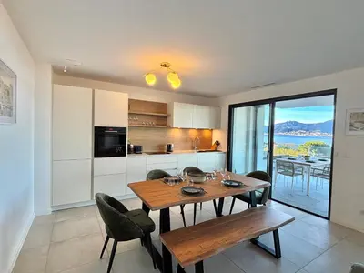 a kitchen and dining room with a wooden table and chairs at Appartement vue mer Royal Palm Porticcio in Porticcio
