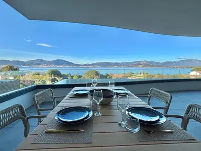 a table with plates and glasses on a balcony at Appartement vue mer Royal Palm Porticcio in Porticcio