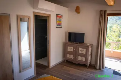 a room with a television and a door to a balcony at A l'Orée du Maquis Villa 6 personnes in Bonifacio