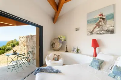 a bedroom with a bed and a view of the ocean at AZUR E CASTELLU - CORSE SUD - Pied à terre IDEAL in Calcatoggio