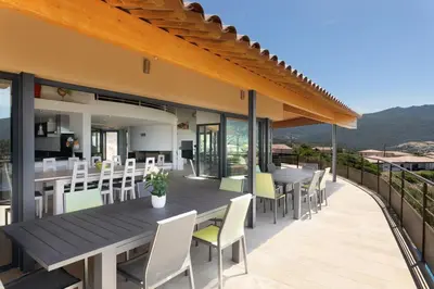 a patio with a wooden table and chairs at AZUR E CASTELLU - CORSE SUD - Pied à terre IDEAL in Calcatoggio