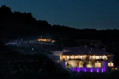 a house lit up at night with purple lights at AZUR E CASTELLU - CORSE SUD - Pied à terre IDEAL in Calcatoggio