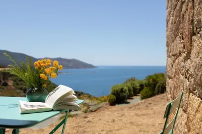 a book sitting on a table with a vase of flowers at AZUR E CASTELLU - CORSE SUD - Pied à terre IDEAL in Calcatoggio