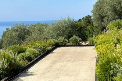 an empty garden with bushes and the ocean in the background at AZUR E CASTELLU - CORSE SUD - Pied à terre IDEAL in Calcatoggio