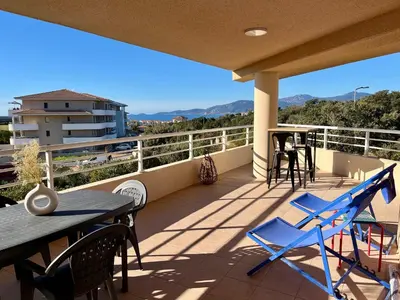 a balcony with tables and chairs and mountains in the background at Très beau T3 5 min plage à pieds in Albitreccia