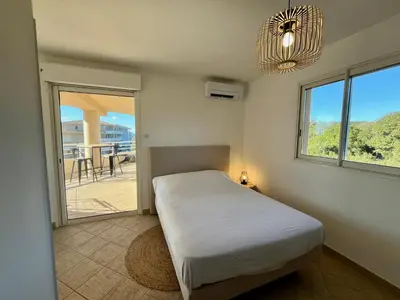 a bedroom with a bed and a large window at Très beau T3 5 min plage à pieds in Albitreccia