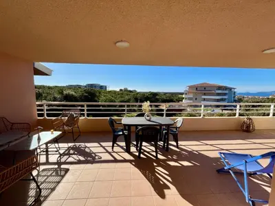 a patio with a table and chairs on a balcony at Très beau T3 5 min plage à pieds in Albitreccia