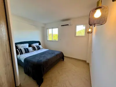 a bedroom with a bed and two windows at Très beau T3 5 min plage à pieds in Albitreccia
