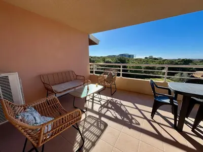 a balcony with a table and chairs and a view of the city at Très beau T3 5 min plage à pieds in Albitreccia