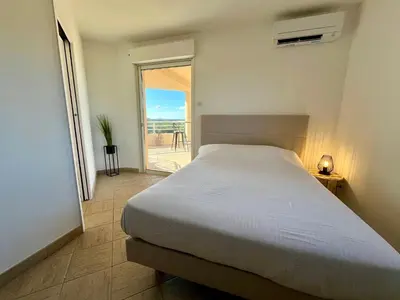 a bedroom with a bed and a view of the ocean at Très beau T3 5 min plage à pieds in Albitreccia