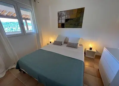 a bedroom with a large bed in a room with windows at Résidence U Sognu in Porto-Vecchio