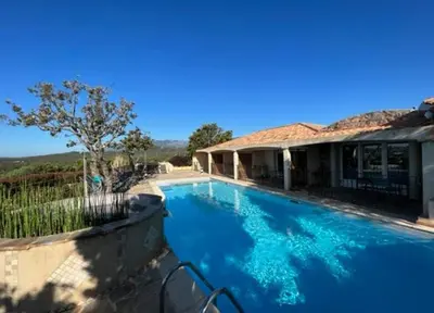 a large blue swimming pool in front of a house at Résidence U Sognu in Porto-Vecchio