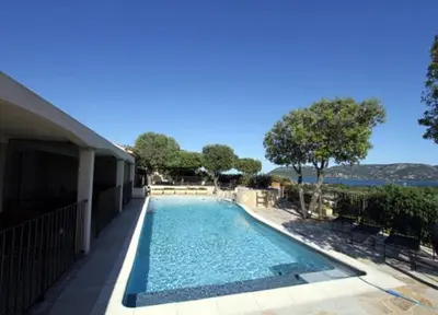 a swimming pool with chairs next to a house at Résidence U Sognu in Porto-Vecchio