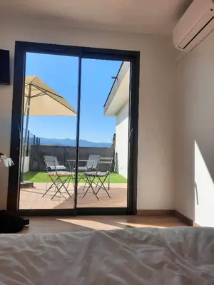 a bedroom with a sliding glass door with chairs and an umbrella at Studio neuf porticcio in Porticcio