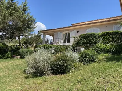 a house with a yard with bushes and trees at Appartement vue mer avec accès privé à la plage in Lecci