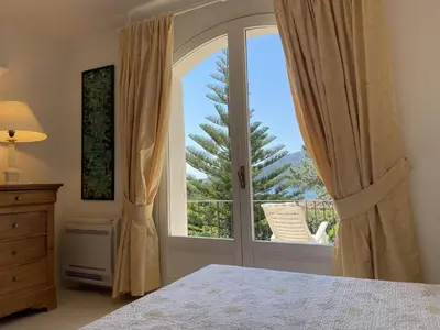 a bedroom with a bed and a large window at Appartement vue mer avec accès privé à la plage in Lecci