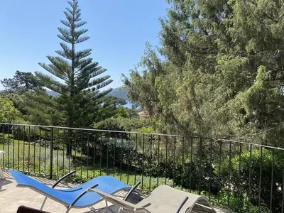 a pair of chairs on a balcony with trees at Appartement vue mer avec accès privé à la plage in Lecci
