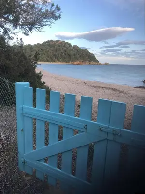 a blue fence on a beach with the ocean at Appartement vue mer avec accès privé à la plage in Lecci