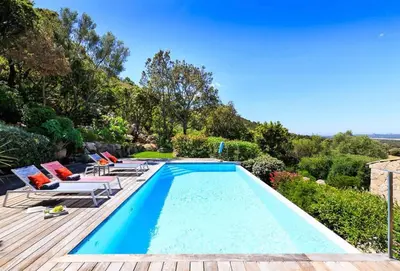 a swimming pool with chaise lounge chairs and a house at Villa en pierre avec piscine chauffée, à proximité des plus belles plages du sud de la Corse ! in Figari