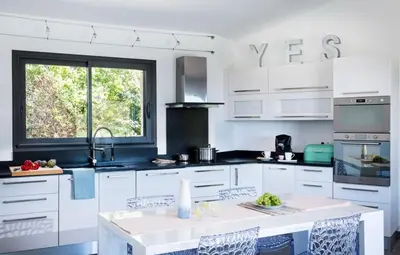 a kitchen with white cabinets and a large window at Villa en pierre avec piscine chauffée, à proximité des plus belles plages du sud de la Corse ! in Figari