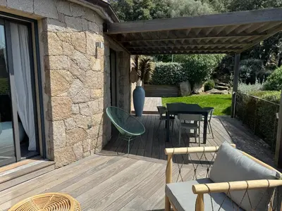 a patio with a table and chairs on a wooden deck at Villa en pierre avec piscine chauffée, à proximité des plus belles plages du sud de la Corse ! in Figari