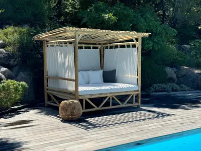 a gazebo sitting on a wooden deck next to a pool at Villa en pierre avec piscine chauffée, à proximité des plus belles plages du sud de la Corse ! in Figari