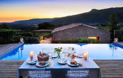 a table set for a meal next to a swimming pool at Villa en pierre avec piscine chauffée, à proximité des plus belles plages du sud de la Corse ! in Figari