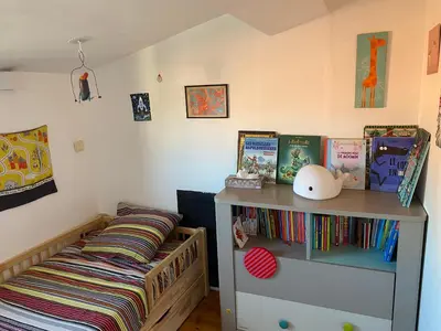 a childs room with a bed and a shelf with books at T4 Terrasses Vieille ville, Ajaccio in Ajaccio