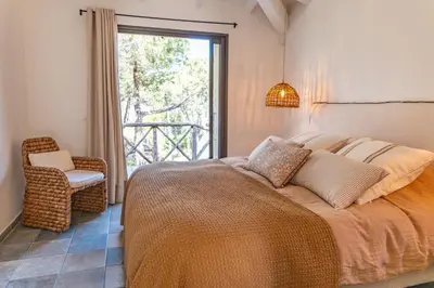 a bedroom with a bed and a chair and a window at Casa Rocca Di Pianotolli in Pianottoli-Caldarello