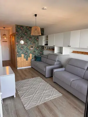 a living room with two couches and a kitchen at Studio les pieds dans l'eau in Santa-Lucia-di-Moriani