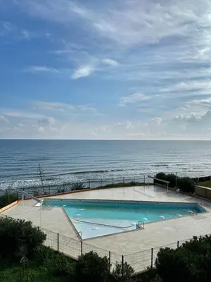 a swimming pool with the ocean in the background at Studio les pieds dans l'eau in Santa-Lucia-di-Moriani