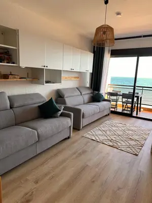 a living room with a couch and a table with a view at Studio les pieds dans l'eau in Santa-Lucia-di-Moriani