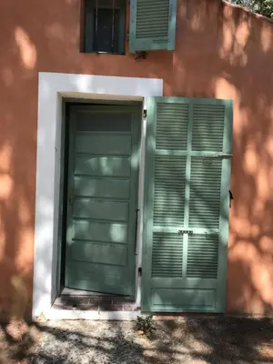 a green door and a window on a building at Mini villa avec jardin in Borgo