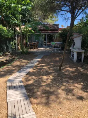 a garden with a wooden pathway leading to a house at Mini villa avec jardin in Borgo