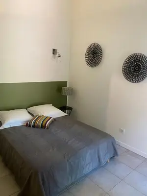 a bedroom with a bed and two mirrors on the wall at Mini villa avec jardin in Borgo
