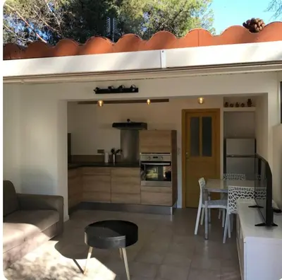a kitchen and living room with a couch and a table at Mini villa avec jardin in Borgo