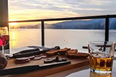 a table with a glass of wine and cookies and a view of the water at Superbe T3 front de mer au centre de Propriano in Propriano