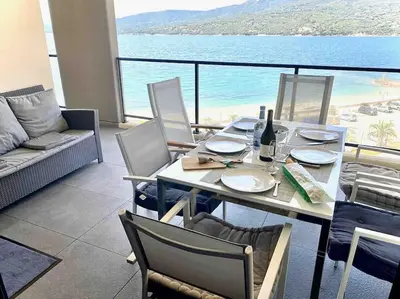 a dining table and chairs with a view of the ocean at Superbe T3 front de mer au centre de Propriano in Propriano