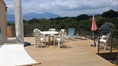 a patio with a table and chairs on a deck at Vue Panoramique in Porticcio