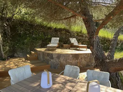 a patio with a table and chairs under a tree at Casa Mimosa in Piana