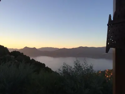 a view of a lake with the sun setting over the mountains at Casa Mimosa in Piana