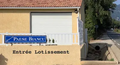 a house with a garage door and a sign on it at La Carpe Diem in Cervione