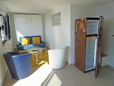 a living room with a couch and a refrigerator at So Leil So Fun à Porticcio - 45m2 - Grand lit 180 - Plage à pied - Wifi fibre - Terrasse in Porticcio