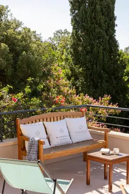 a wooden bench on a patio with a table and a chair at Villa MARINARCA sitew Porto Vecchio Marina di Fiori Vue mer piscine chauffée Clim plage à pied tennis in Porto-Vecchio