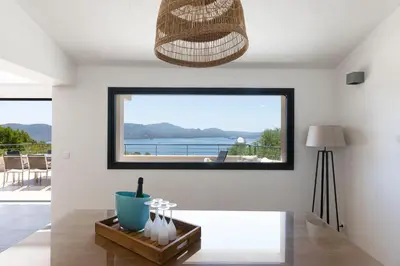 a living room with a table and a large window at Villa MARINARCA sitew Porto Vecchio Marina di Fiori Vue mer piscine chauffée Clim plage à pied tennis in Porto-Vecchio