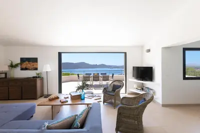 a living room with a couch and a table with chairs at Villa MARINARCA sitew Porto Vecchio Marina di Fiori Vue mer piscine chauffée Clim plage à pied tennis in Porto-Vecchio