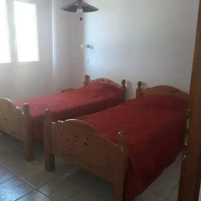 two beds in a bedroom with red sheets and a window at Residence les Lavandes in Olmeto