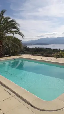 a blue swimming pool with a view of the ocean at Residence les Lavandes in Olmeto