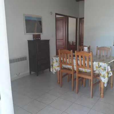 a dining room with a table and wooden chairs at Residence les Lavandes in Olmeto