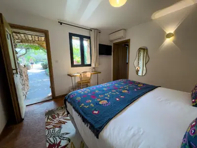 a bedroom with a bed with a blue blanket on it at Domaine Pozzo di Mastri hôtel & spa in Figari